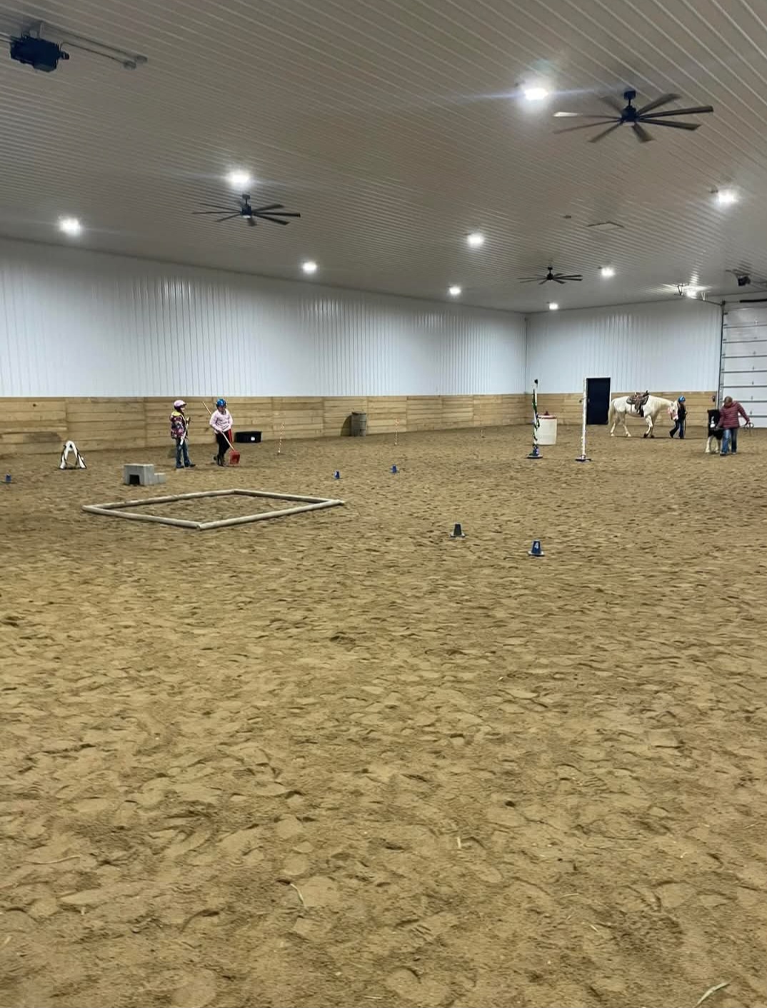 Kids working through an obstacle course with a horse in the indoor arena